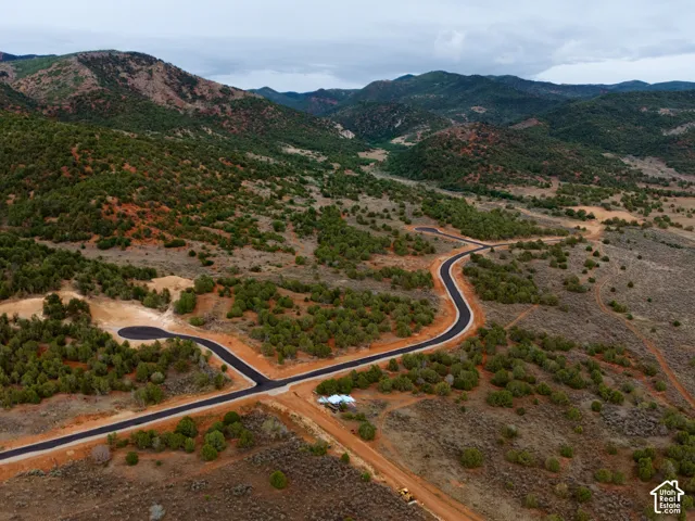 Expansive acreage featuring paved roads, undulating terrain, native vegetation, and a prominent mountain backdrop