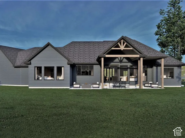 Exterior rear elevation featuring horizontal siding, a covered patio with timber support beams, a multi-gabled roofline, and a stone-surfaced patio area
