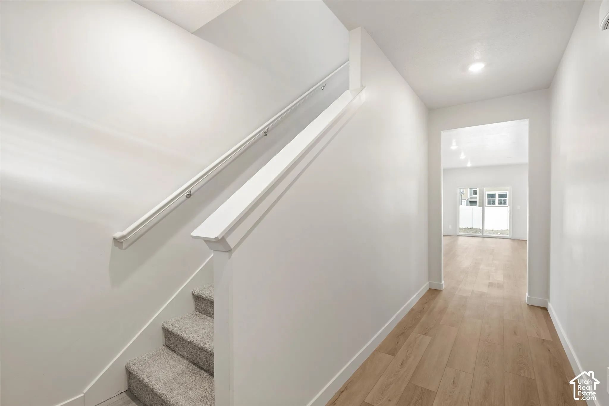 **DISCLAIMER** Interior package may vary.  Staircase featuring a painted wood handrail, neutral-toned carpeted steps, wood-finish flooring, and recessed ceiling lighting