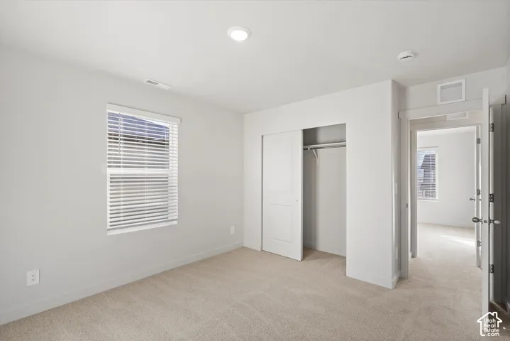 **DISCLAIMER** Interior package may vary. Neutral-toned carpeted flooring, recessed lighting, window with horizontal blinds, and closet with a paneled door