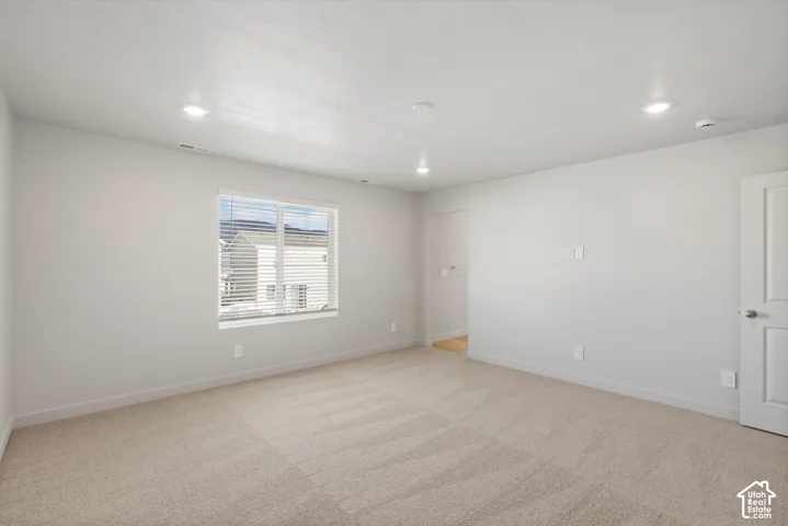 **DISCLAIMER** Interior package may vary. Neutral-toned interior space featuring wall-to-wall carpeting, recessed ceiling lighting, and a single-hung window with installed blinds