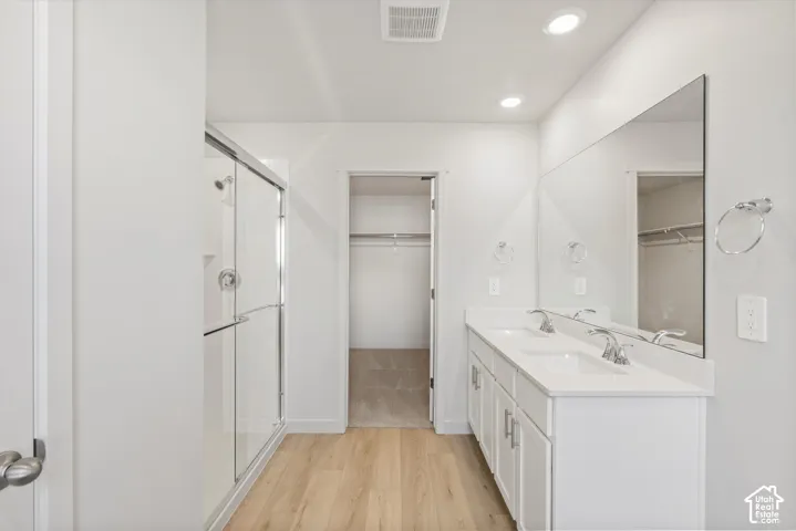 **DISCLAIMER** Interior package may vary. Dual-sink vanity with a solid-surface countertop, floor-to-ceiling plate glass mirror, walk-in shower with a glass enclosure, and wood-finish flooring