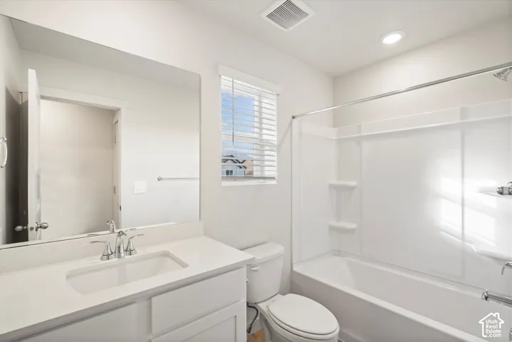 **DISCLAIMER** Interior package may vary. Bathroom featuring a vanity with a white countertop and rectangular undermount sink, a large wall-mounted mirror, a tub-shower combination with built-in shelving, and horizontal window blinds