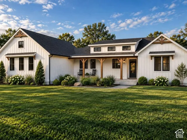 Modern farmhouse exterior featuring vertical board-and-batten siding, dark-framed windows, a covered porch with timber support beams, and a roofline accented by decorative gables