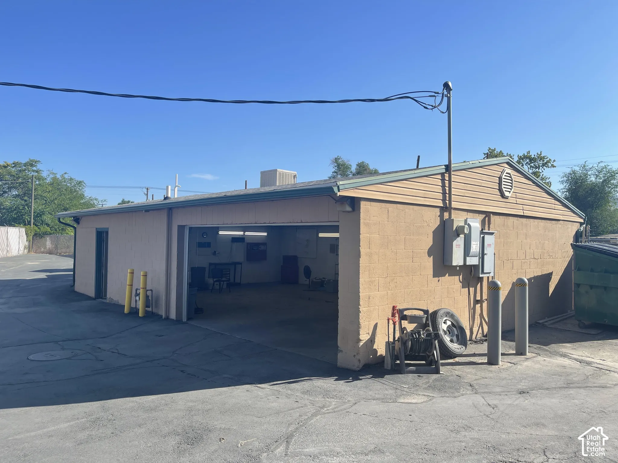 Detached building featuring concrete block construction, asphalt-paved exterior surface, and large open garage bay
