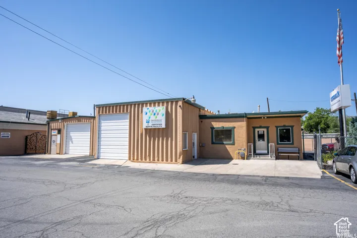 Commercial facility featuring metal-siding construction, two grade-level roll-up doors, paved exterior parking, and an elevated entry platform