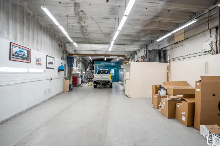 Industrial workshop space featuring high ceilings, concrete flooring, linear overhead lighting, and an integrated paint booth