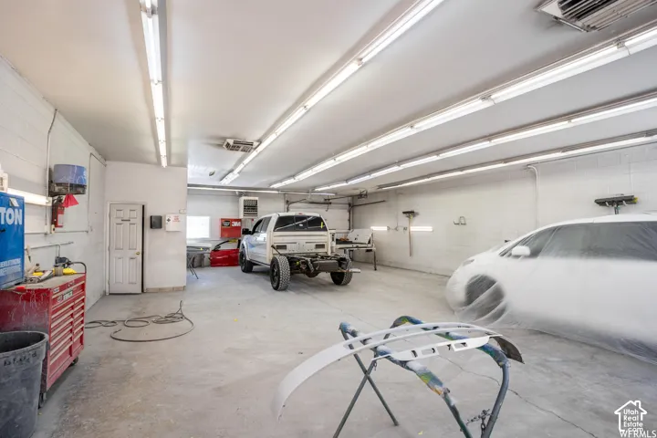 Spacious garage featuring concrete flooring, painted masonry walls, and extensive linear fluorescent overhead lighting