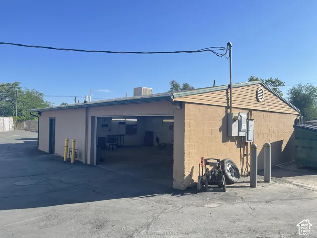 Detached building featuring concrete block construction, asphalt-paved exterior surface, and large open garage bay