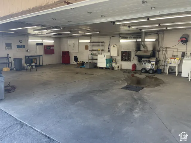Expansive workshop featuring a concrete floor, high-output overhead lighting, integrated exhaust system, and wall-mounted plumbing utility