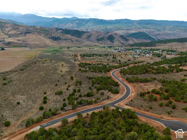Aerial perspective of expansive land featuring paved roadways, native vegetation, and a mountainous backdrop