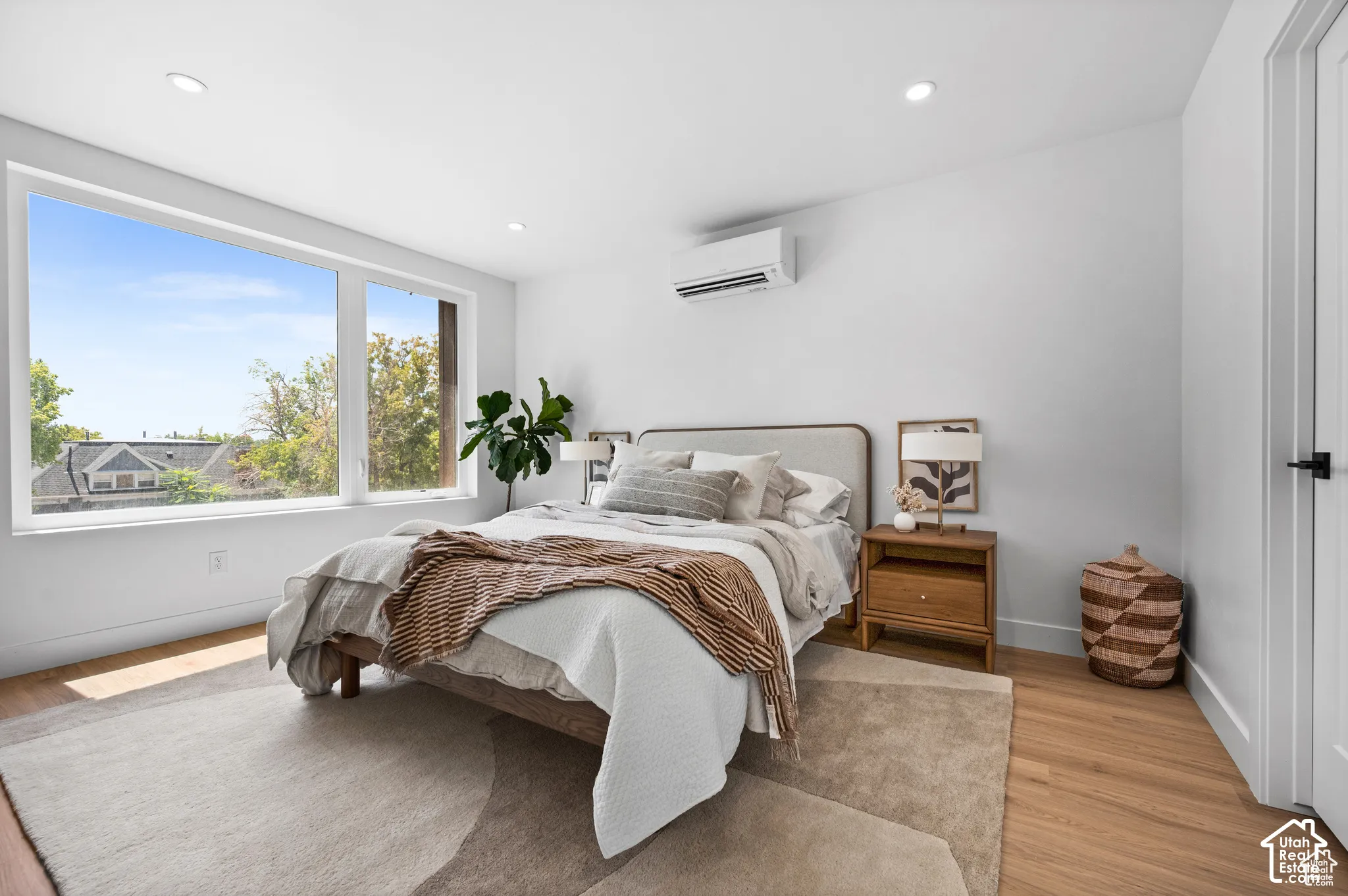 Large picture window, recessed lighting, wood-finish flooring, and wall-mounted climate control unit