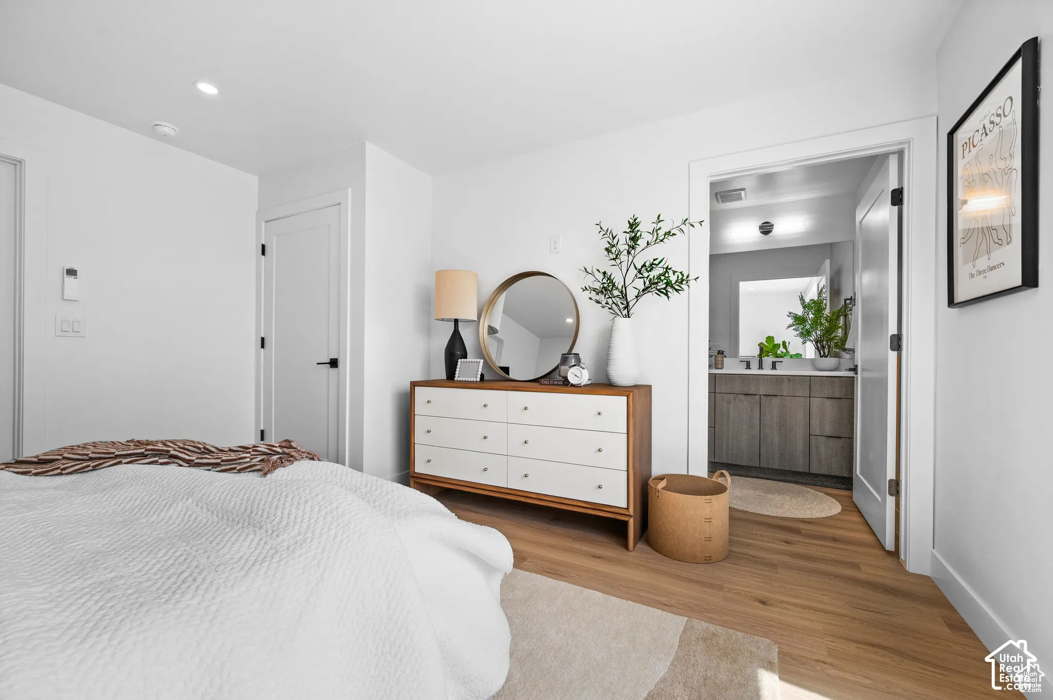 Wood-finish flooring, white walls, recessed ceiling lighting, and solid-core doors with matte black hardware