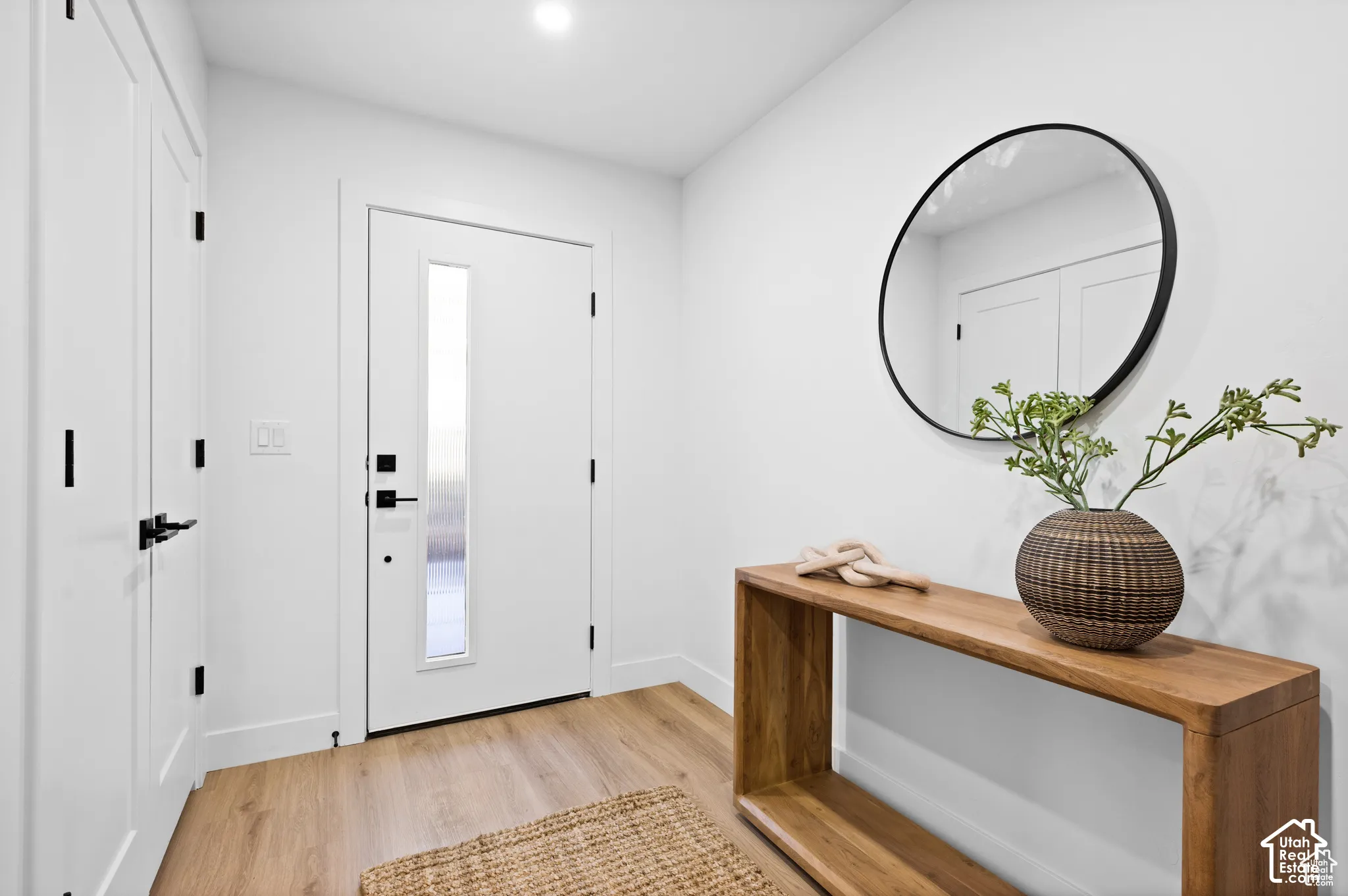 Entryway featuring wood-finish flooring, a white front door with a vertical glass panel, recessed lighting, and matte black hardware throughout