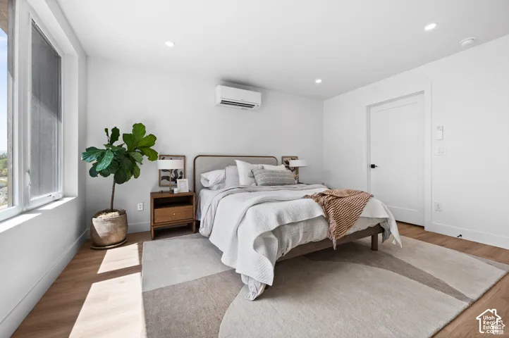 Wood-finish flooring, recessed lighting, large paneled window, and wall-mounted ductless climate control unit