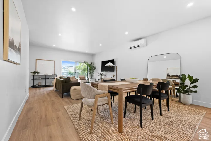Open-concept living space featuring wood-finish flooring, recessed lighting, and a wall-mounted ductless climate control unit