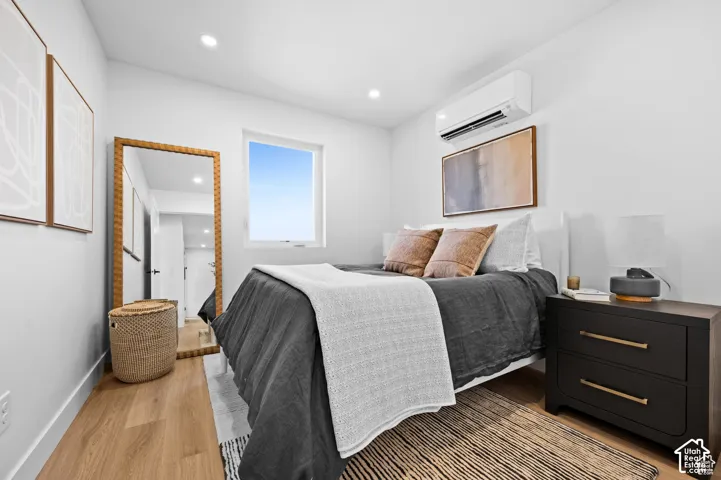 Room featuring wood-finish flooring, recessed lighting, and a wall-mounted ductless climate control unit