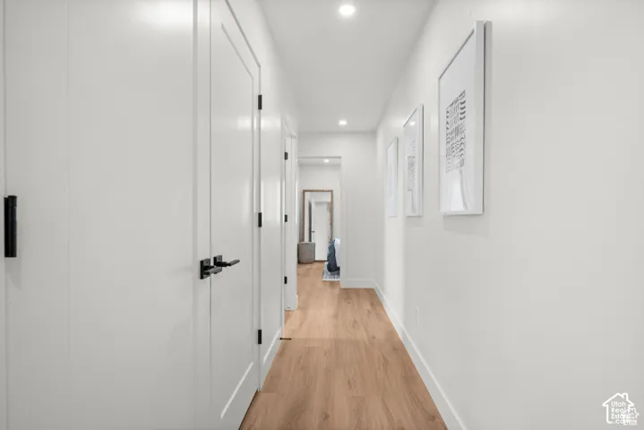 Hallway featuring wood-finish flooring, recessed lighting, and solid-core interior doors with matte black hardware