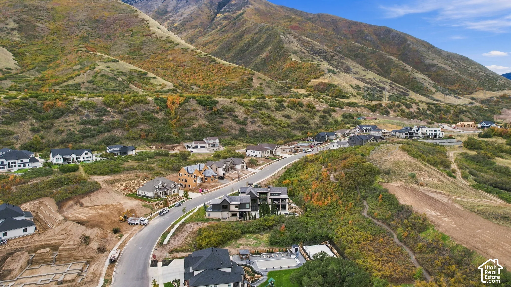 Aerial perspective of a residential neighborhood featuring mountain topography, paved streets, and natural landscape borders