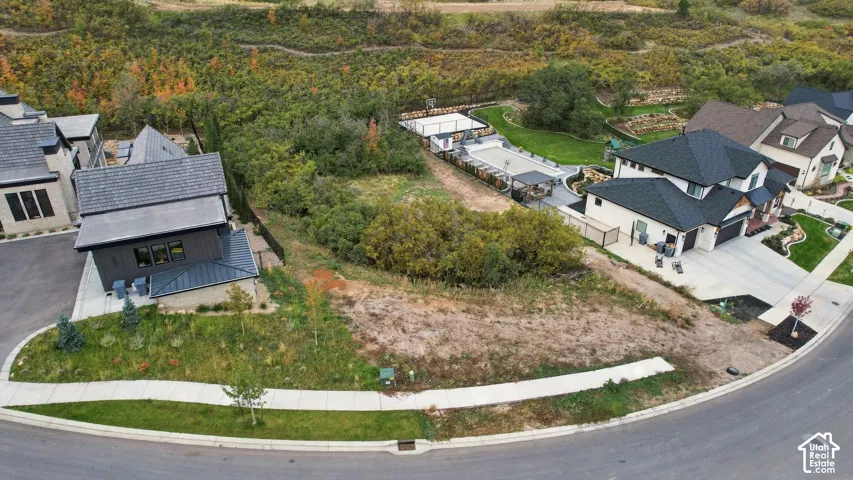 Aerial perspective of properties featuring hardscaped driveways, multi-pitched shingle roofing, and an integrated sport court