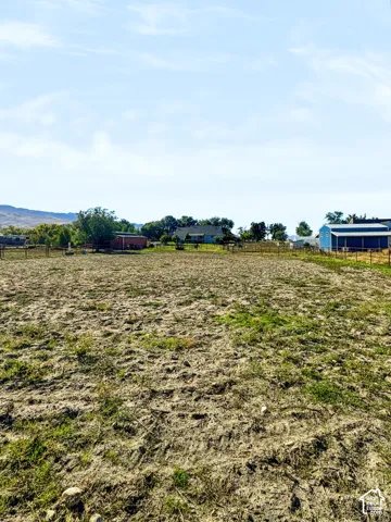 Open pasture with perimeter fencing, mountain backdrop and barn.