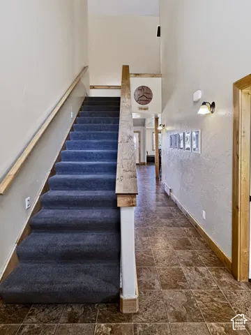 Here are a few ways to fix and polish your sentence, depending on where you are using it:Option 1: Natural & Smooth (Best Overall)"The entryway features a staircase leading to the second story with carpeted steps and a light-finish wood handrail, with