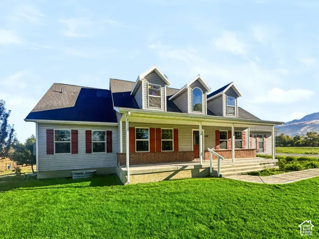 Multi-gabled exterior featuring horizontal siding, brick masonry detailing, decorative shutters, dormer windows, and a covered front porch