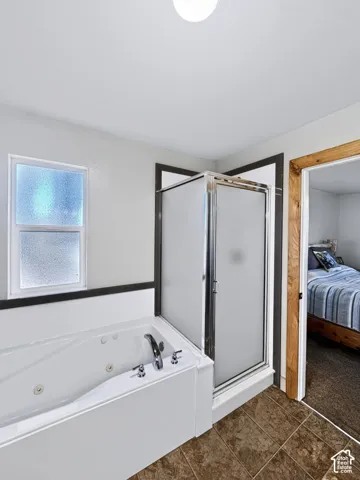 Ensuite bathroom features a jetted tub, glass-enclosed shower with frosted panels and tile flooring.