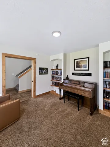 Formal living room off the entryway featuring natural wood-finish door casing, two arched built-in shelving units, and natural light.