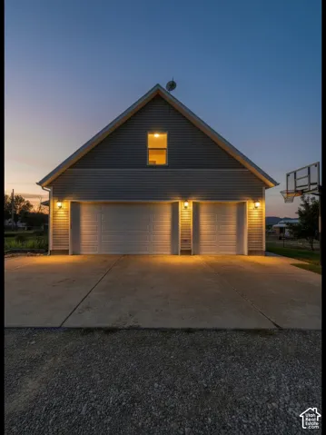 Attached 3-car garage featuring horizontal siding, two overhead garage doors, exterior wall-mounted lighting, and a concrete driveway.