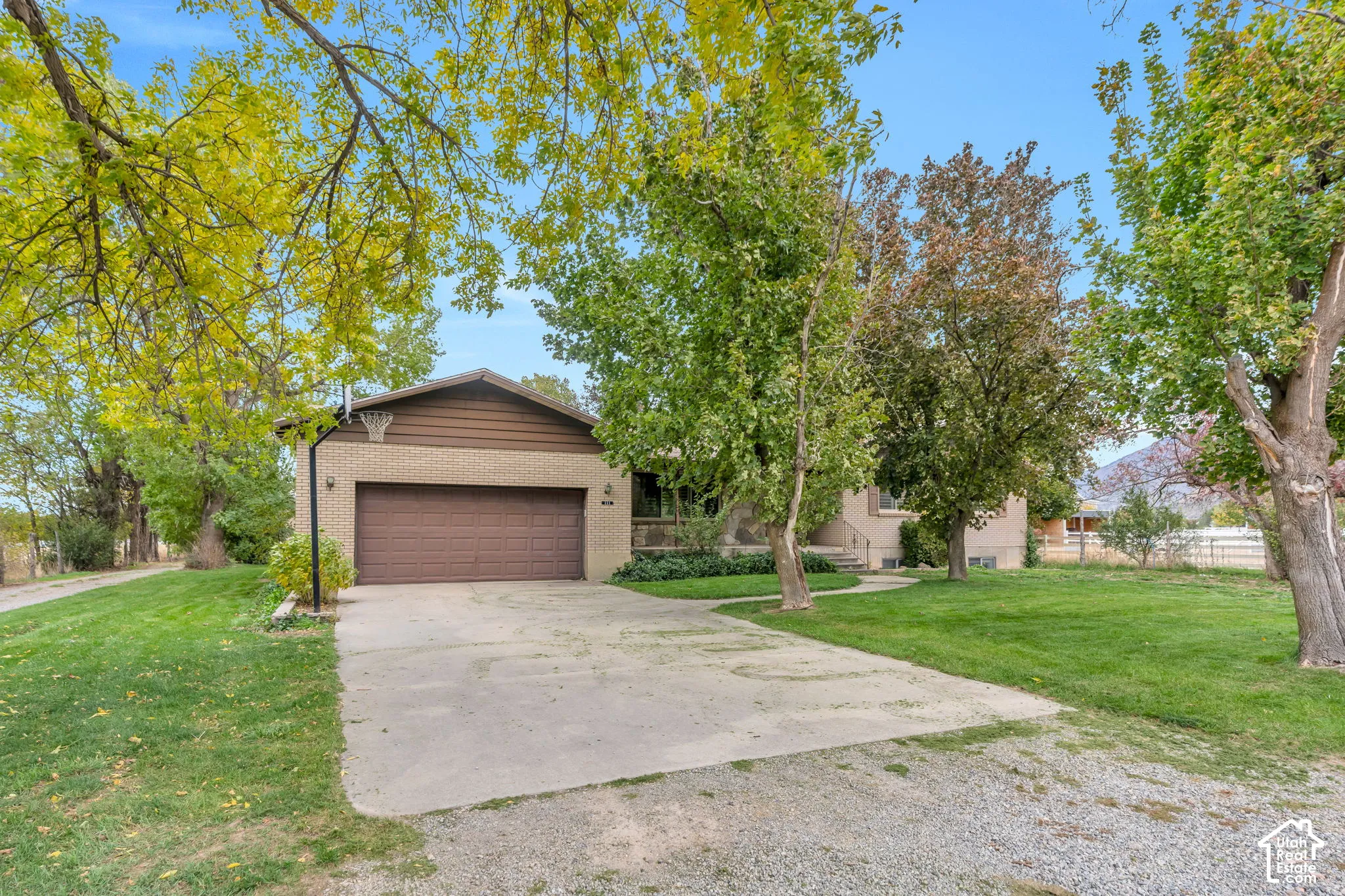 Single-story residence featuring a brick facade, attached two-car garage, concrete driveway, and mature landscaping