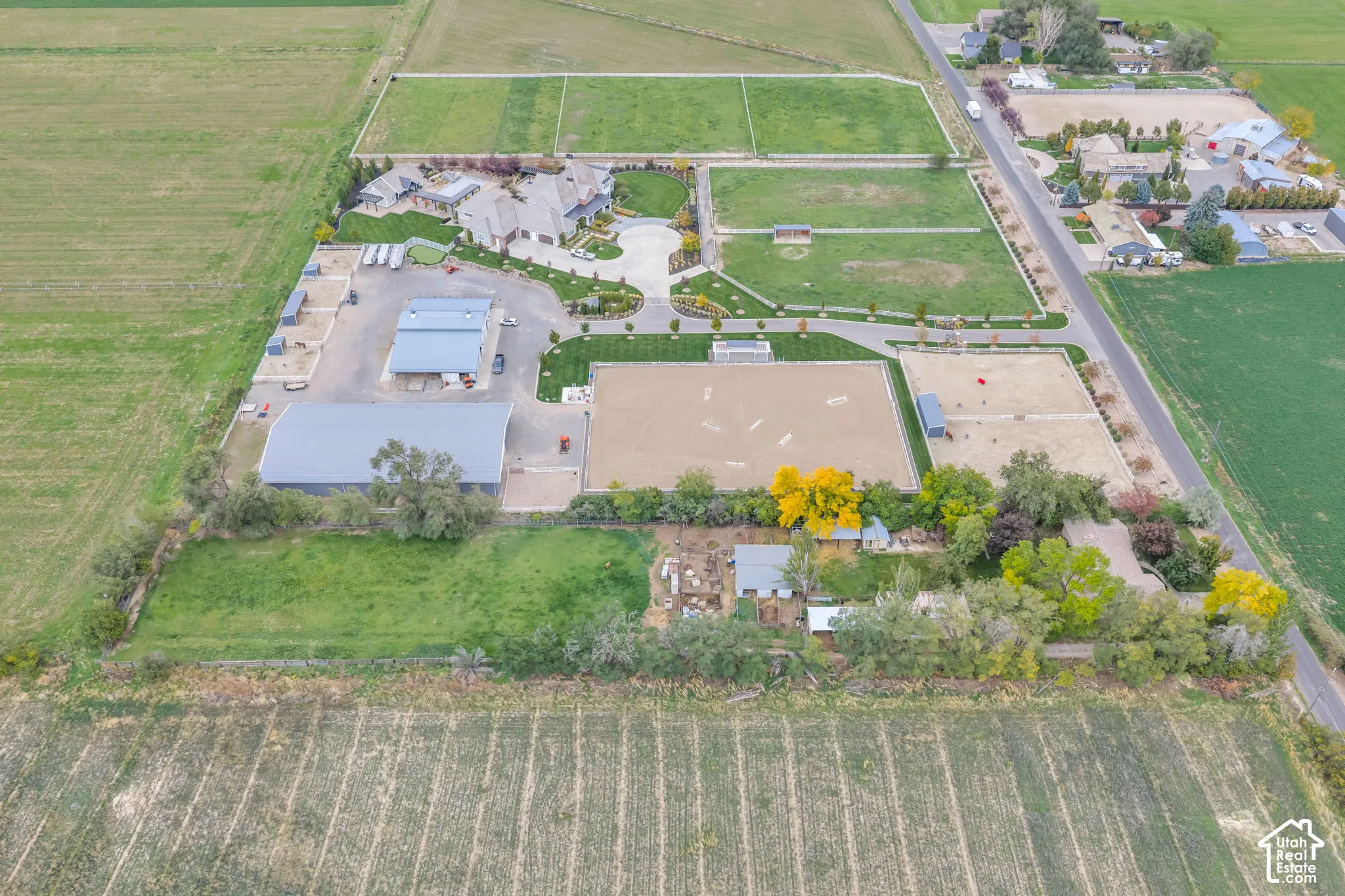 Expansive acreage featuring a multi-structure compound, large-scale riding arena, paved circular driveway, and segmented outdoor paddocks