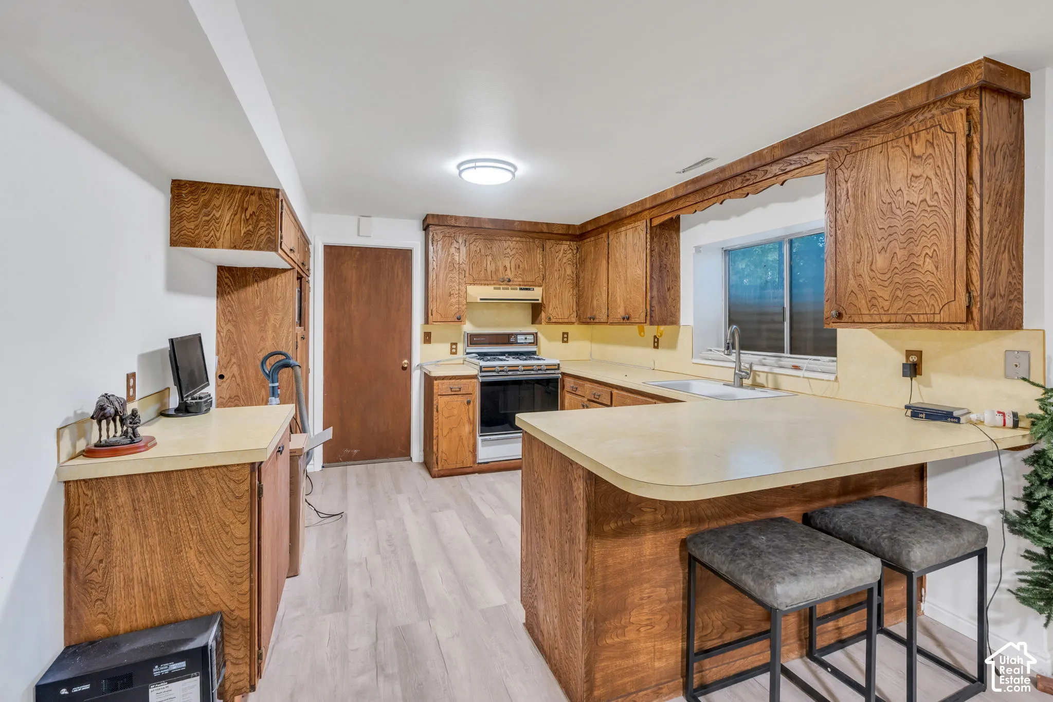 Kitchen featuring wood cabinetry, solid surface countertops, a peninsula with bar seating space, and wood-finish flooring