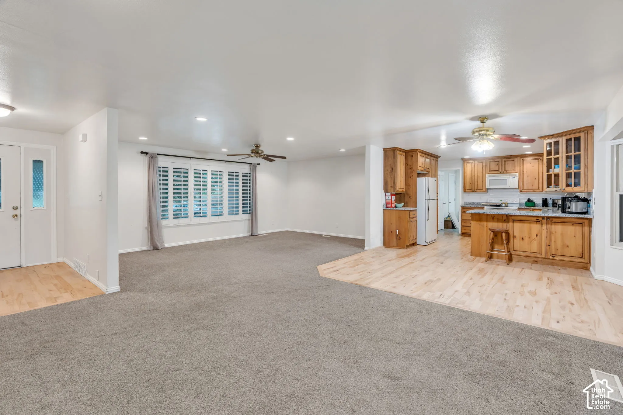 Open-concept layout featuring wood-finish flooring, recessed lighting, ceiling fans, plantation shutters, and wood cabinetry