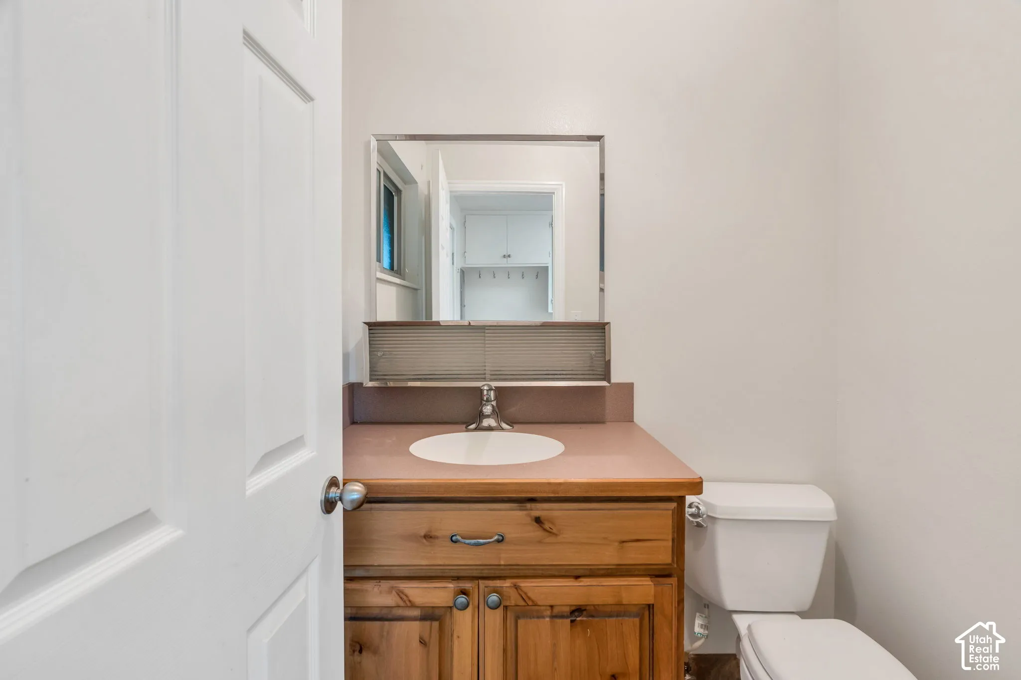 Wood-finish vanity featuring an integrated oval sink, solid-surface countertop, rectangular mirror with an attached shelf, and chrome fixtures