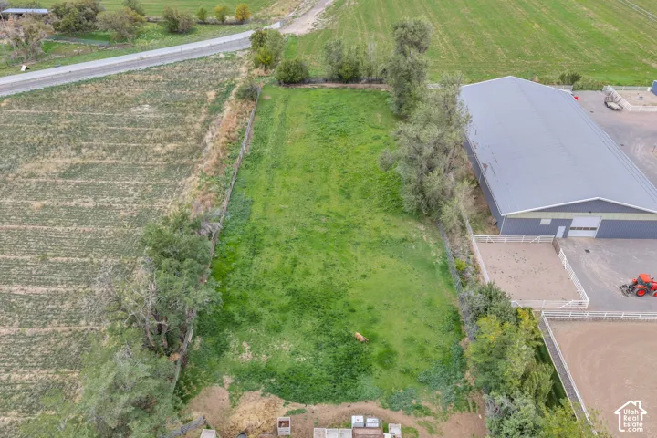 Expansive parcel featuring open green space, mature trees, a metal-sided structure, and enclosed outdoor arenas