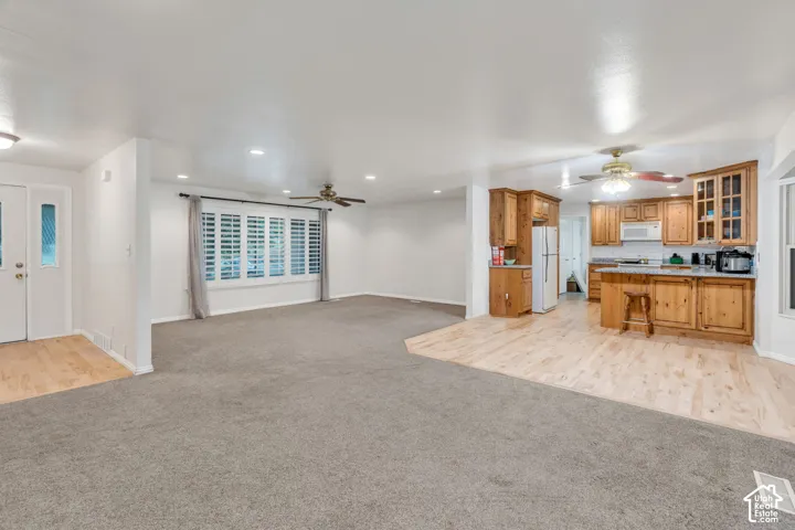 Open-concept layout featuring wood-finish flooring, recessed lighting, ceiling fans, plantation shutters, and wood cabinetry
