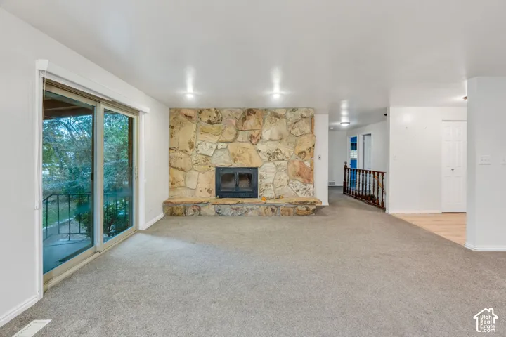 Floor-to-ceiling stone hearth with a fireplace insert, glass sliding door, recessed lighting, and wooden handrail with balusters