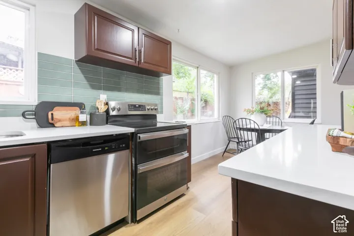 Kitchen featuring solid-surface countertops, wood-finish cabinetry, stainless steel appliances, and a glass-tile backsplash