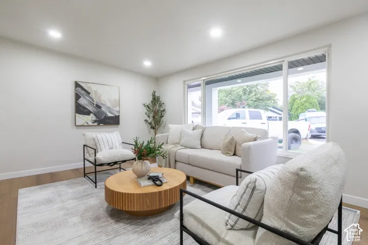 Large picture window, recessed ceiling lighting, and wood-finish flooring