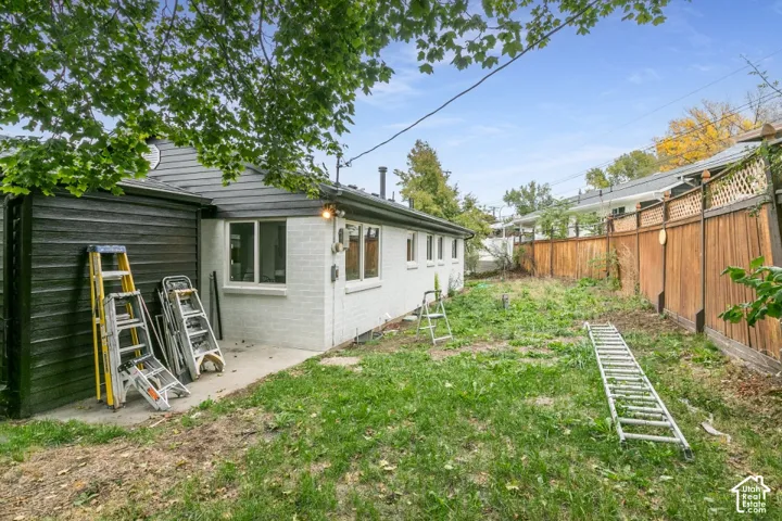 Exterior featuring painted brick and horizontal lap siding, concrete patio, and wood privacy fencing