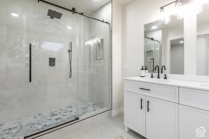 Walk-in shower featuring floor-to-ceiling tile, pebble-stone flooring, and a sliding glass enclosure with matte black hardware