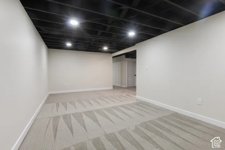 Neutral walls, carpeted flooring, and an exposed ceiling finished in black with recessed lighting