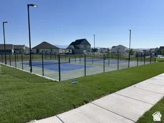 Community sports courts featuring fenced-in playing surfaces, integrated netting, pole-mounted lighting, and a concrete walkway