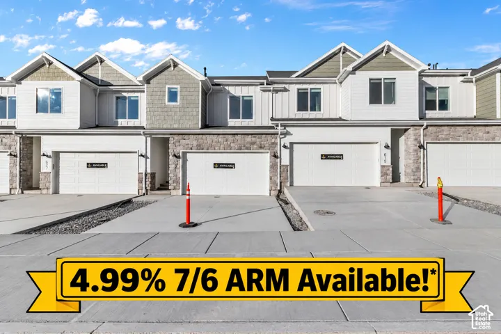 Multi-family architectural exterior featuring stone masonry, vertical siding, multi-gabled rooflines, and double-car garage doors with concrete driveways