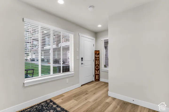 Entryway featuring wood-finish flooring, recessed lighting, and a white paneled door with hardware