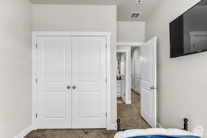 Interior room featuring double-panel closet doors, crisp white trim, neutral wall coloring, and wall-to-wall carpeting