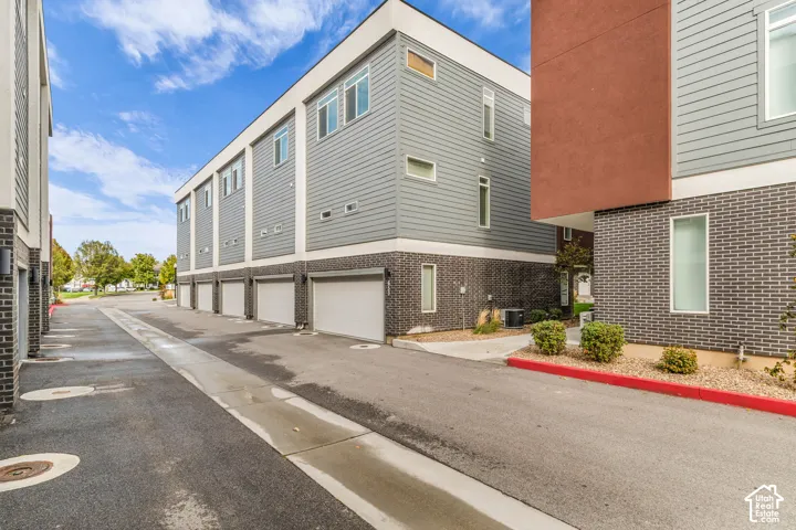 Modern exterior featuring a mixed-material facade of brick veneer, horizontal siding, and stucco finish, multi-level design with uniform carriage-style garage doors, and landscaped exterior beds