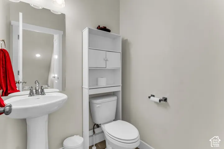 Pedestal sink with polished chrome faucet, rectangular wall-mounted mirror, built-in over-the-toilet storage unit, and polished chrome hardware