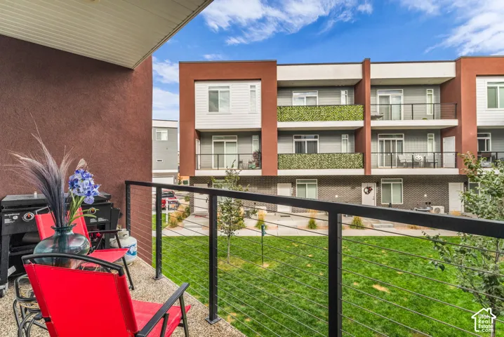 Private balcony featuring exposed aggregate flooring and black metal railing with horizontal cable infill